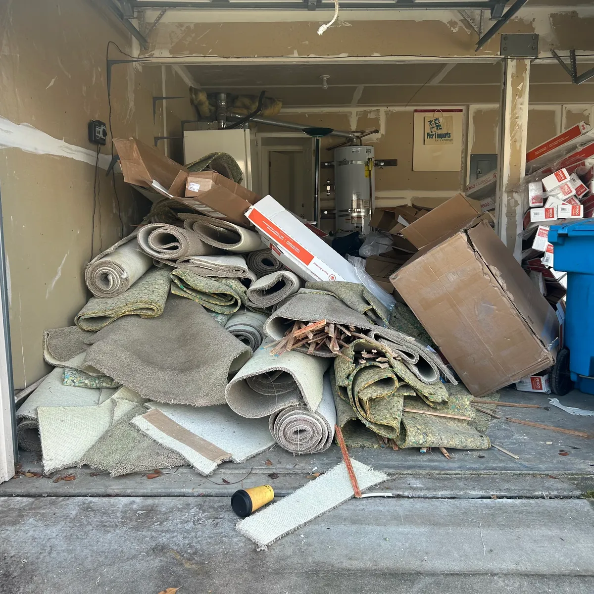 Garage piled with old carpet rolls, padding, and boxes before removal