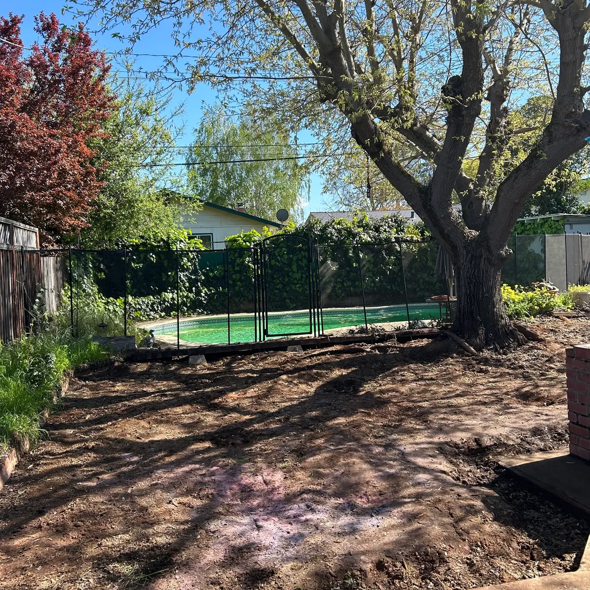 Same backyard cleared to bare dirt after the old deck was torn out and hauled away