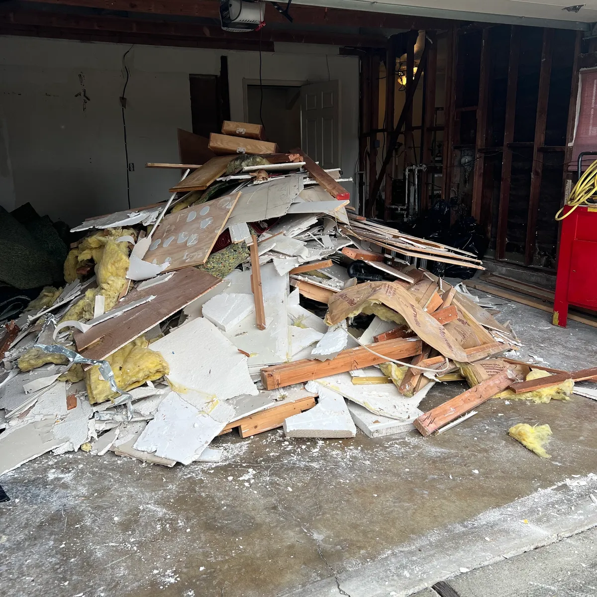 Garage with a large pile of drywall, insulation, and lumber demo debris before removal