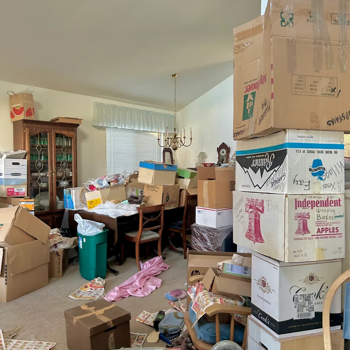 Dining room stacked with moving boxes and furniture before an estate cleanout
