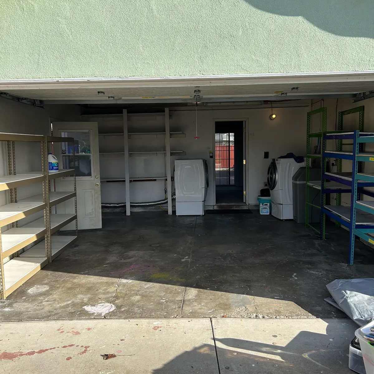 Same garage cleared out with empty shelves and open floor after cleanout